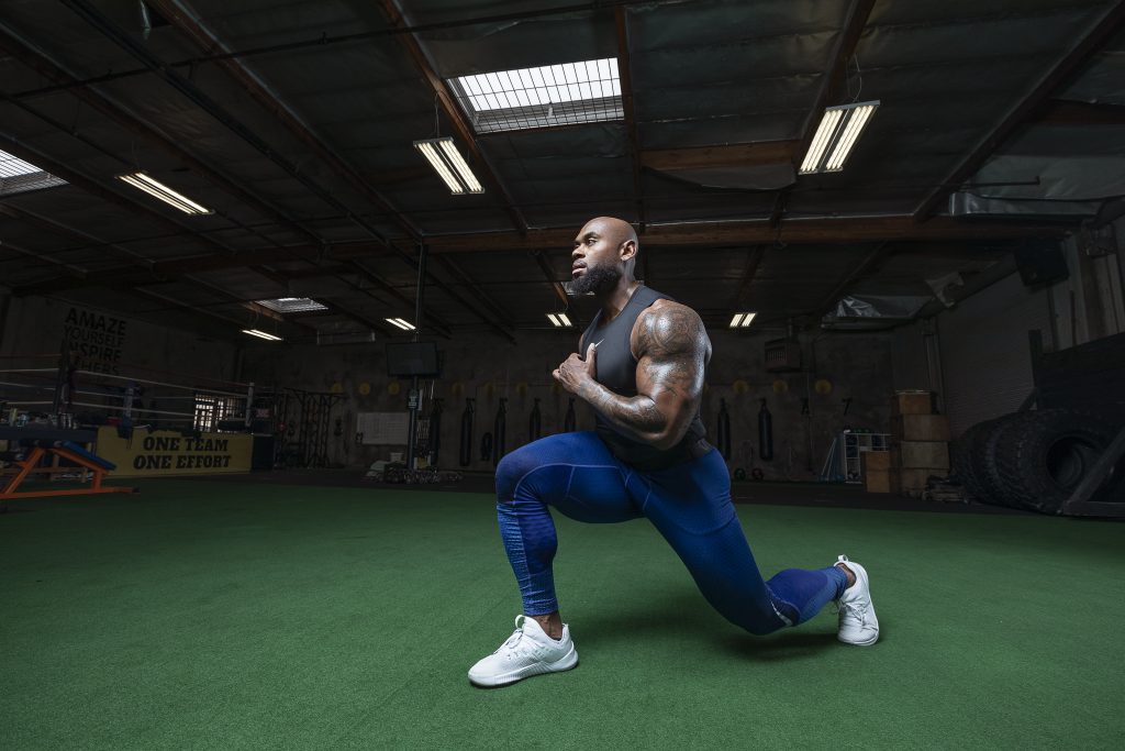 A man doing lunges in a gym.