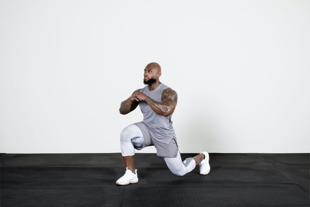 A man doing lunges in a gym.