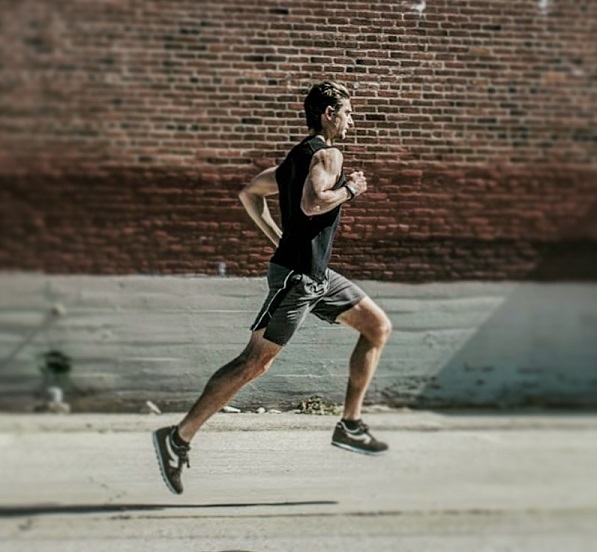 A man in black running on a street.