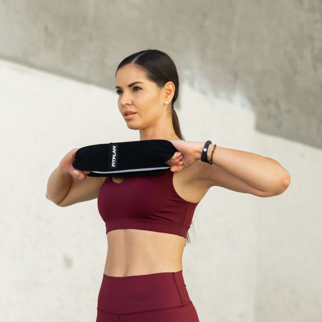 A woman in a red outfit holding a resistance band.